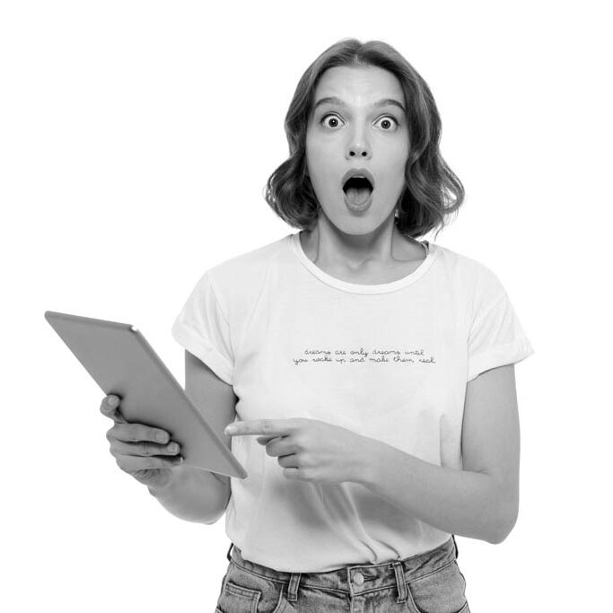 Portrait of a shocked young girl holding tablet computer and looking at camera isolated over white background